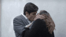 a man in a suit kissing a woman on the forehead