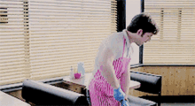 a man in a pink apron and blue gloves is cleaning a couch in a diner