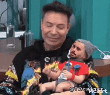 a man is holding a baby with a picture of a man 's face on it .