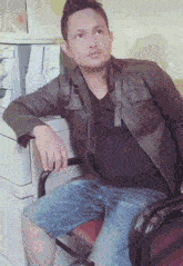 a man in a leather jacket is sitting on a chair