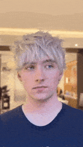 a young man with white hair and blue eyes is wearing a blue shirt that says abercrombie
