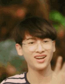 a young man wearing glasses and a striped shirt is smiling and giving a thumbs up