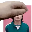a hand is covering a man 's face with a pink background .