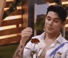a man in a white shirt is holding a red rose .