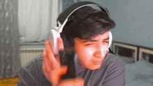 a young man wearing headphones is holding a gun in his hand and making a funny face .