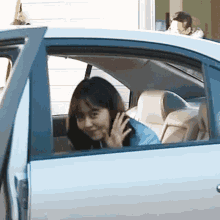 a woman is sitting in the back seat of a car waving