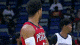 a basketball player in a red jersey is standing next to another player in a white jersey on a court .