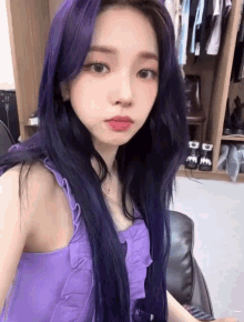 a girl with purple hair is sitting in a chair