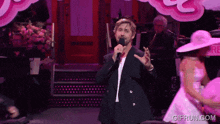 a man singing into a microphone with gifrun.com written on the bottom of the screen