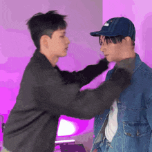 a man wearing a hat and a denim jacket is putting a hand on another man 's neck