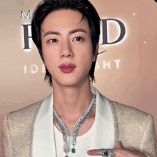 a man wearing a necklace and a ring stands in front of a sign that says id