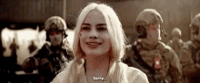 a woman is smiling in front of a group of soldiers and says `` sorry '' .