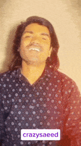 a man with long hair and a mustache is making a funny face while wearing a black polka dot shirt .