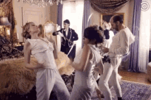 a group of people in white clothes are having a pillow fight in a room .