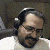 a man with a beard wearing headphones and glasses is smiling