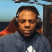 a man wearing headphones and a hoodie with an adidas logo