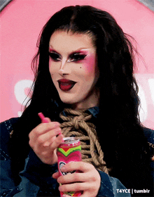 a drag queen is holding a pink can with a rainbow design on it