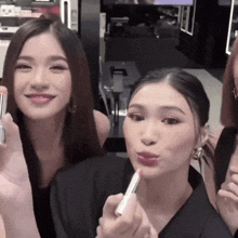a woman is applying lipstick to another woman 's face