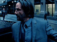a man in a blue suit and tie is walking down a street