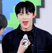 a young man holds a microphone with the number 3 on it