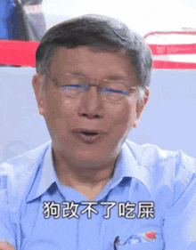 a man wearing glasses and a blue shirt has chinese writing on his shirt