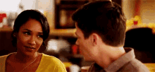 a man and a woman are looking at each other . the woman is wearing a yellow shirt .