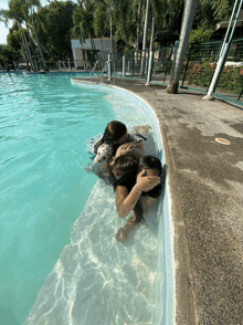 three people are swimming in a pool and one of them is covering her eyes with her hand