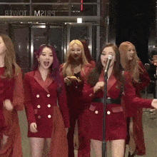 a group of women are singing into a microphone in front of a building that says tower on it