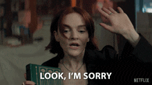 a woman holding a book and saying look i 'm sorry