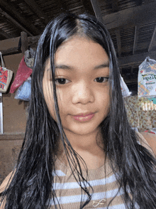 a girl with long black hair is standing in front of a bag that says ritz
