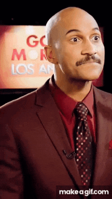 a man in a suit and tie is standing in front of a screen that says go monday los angeles