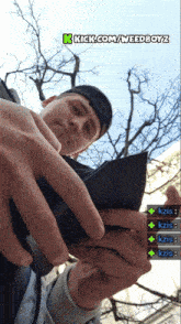 a man is holding a wallet with the words kick.com/weedboyz on the bottom