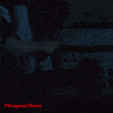 a woman in a dark room with #weaponsmovie written in red