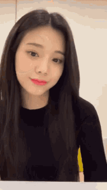 a woman with long black hair and red lips is looking at the camera .
