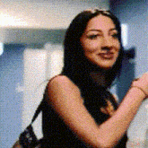 a woman with long black hair is smiling and carrying a black bag