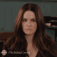 a close up of a woman 's face with a #schitts creek logo in the corner