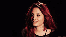 a woman with red hair is smiling and wearing a black shirt