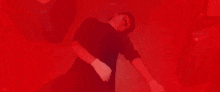 a man is laying on the floor with his arms outstretched in a red light .