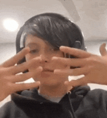 a boy wearing headphones is making a funny face with his hands .