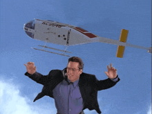 a man in a suit stands in front of a helicopter that says nl395vb