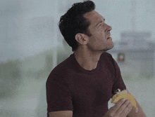 a man in a maroon shirt eating a sandwich