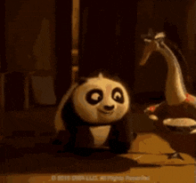 a panda bear is standing next to a duck in a room .