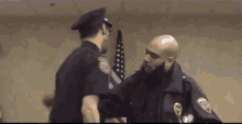 two police officers are standing next to each other and shaking hands in front of an american flag .