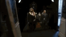 a man in a white robe is walking on a red carpet next to a man in a blue coat