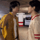 a couple of men are standing next to each other in a parking garage .