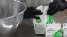 a carton of fresh cream is being opened by a person wearing black gloves