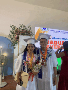 two graduates pose for a photo in front of a sign that says senior high graduation ever