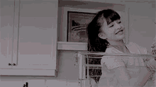 a little girl is standing in a kitchen with a picture on the wall .