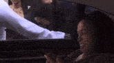 a woman is sitting in a car talking to a man in a white shirt