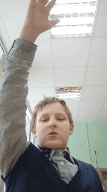 a young boy raises his hand in a classroom